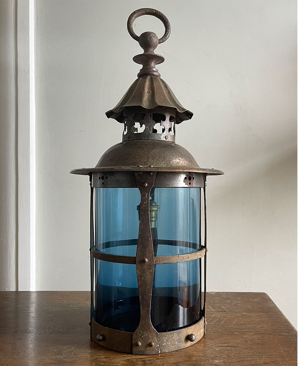 A large Arts & Crafts Hall Lantern. Hand beaten copper top with fleur de lis detailing, smithed iron shade cage Hall lantern with original mouth blown petrol blue glass. Elegant form, scale and colour - SHOP NOW - www.intovintage.co.uk