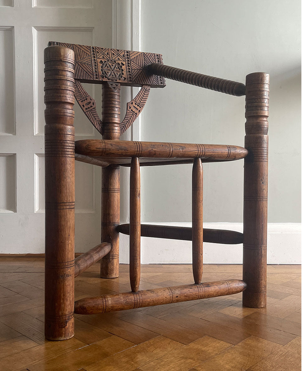 A late 19th century Oak Turners Chair in the Warwick style. With a chip carved back, turned bobbin arms, triangular seat and standing on three turned legs united by stretchers - SHOP NOW - www.intovintage.co.uk