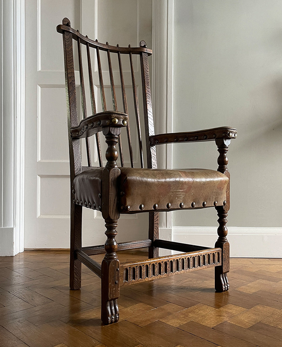 A super solid oak Arts and Crafts styled Carver Chair by the master furniture maker Rupert Griffiths. The style is known as 'Monastic' with this being a Swiss Stick back. The chair has its original leather seat and arms with big old brass studs holding it all in place. The frame is of oak and jointed with oak pegs - SHOP NOW - www.intovintage.co.uk