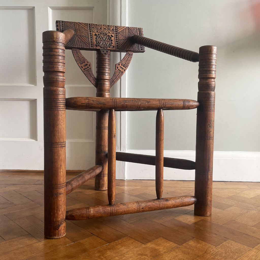 A late 19th century Oak Turners Chair in the Warwick style. With a chip carved back, turned bobbin arms, triangular seat and standing on three turned legs united by stretchers - SHOP NOW - www.intovintage.co.uk