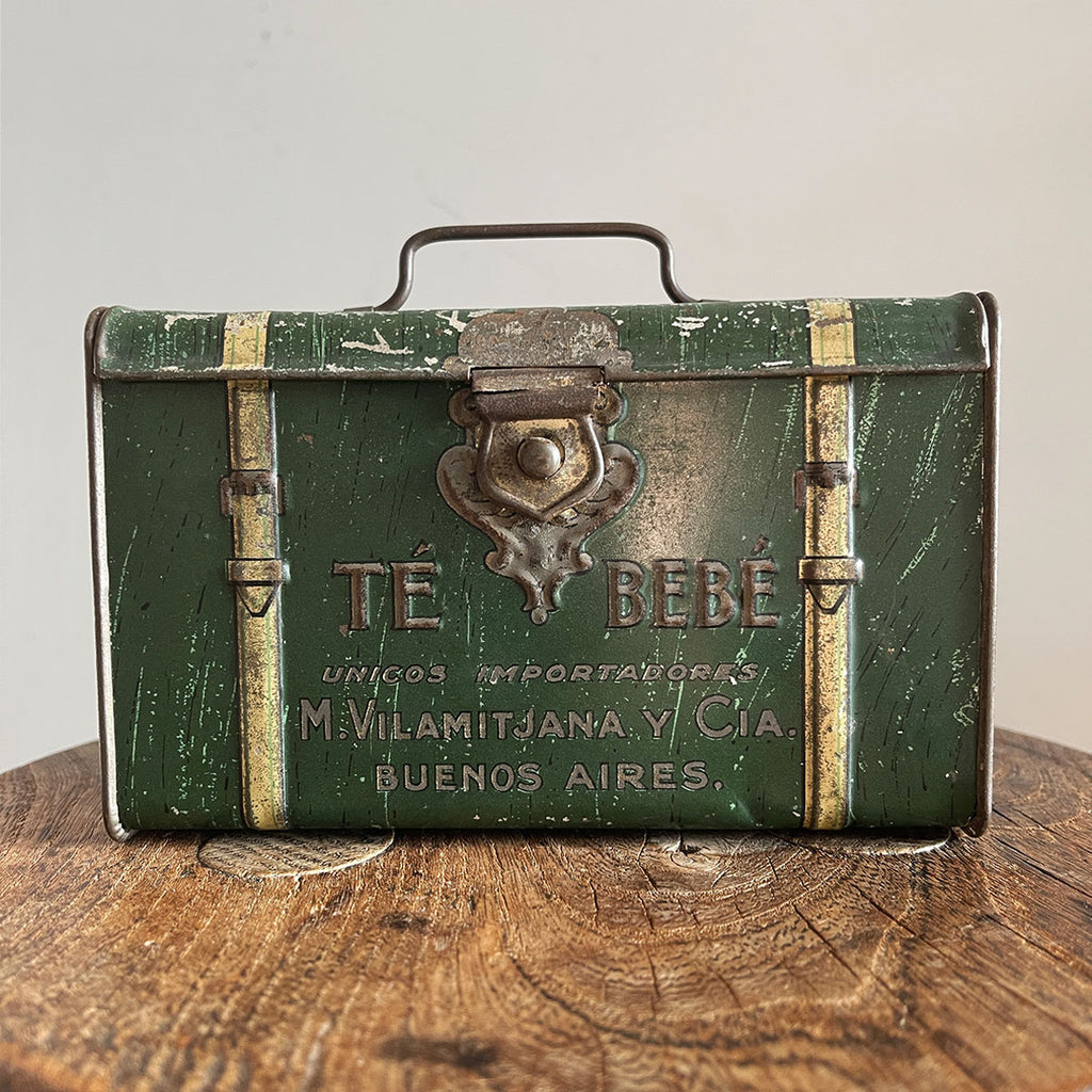 A 'Te Bebe' Buenos Aires Tea Tin in the shape of miniature steamer trunk. It has a little handle on the top lid and each end sees an embossed image of a child carrying a tea box. A rare tin that has travelled all the way from Argentina - SHOP NOW - www.intovintage.co.uk