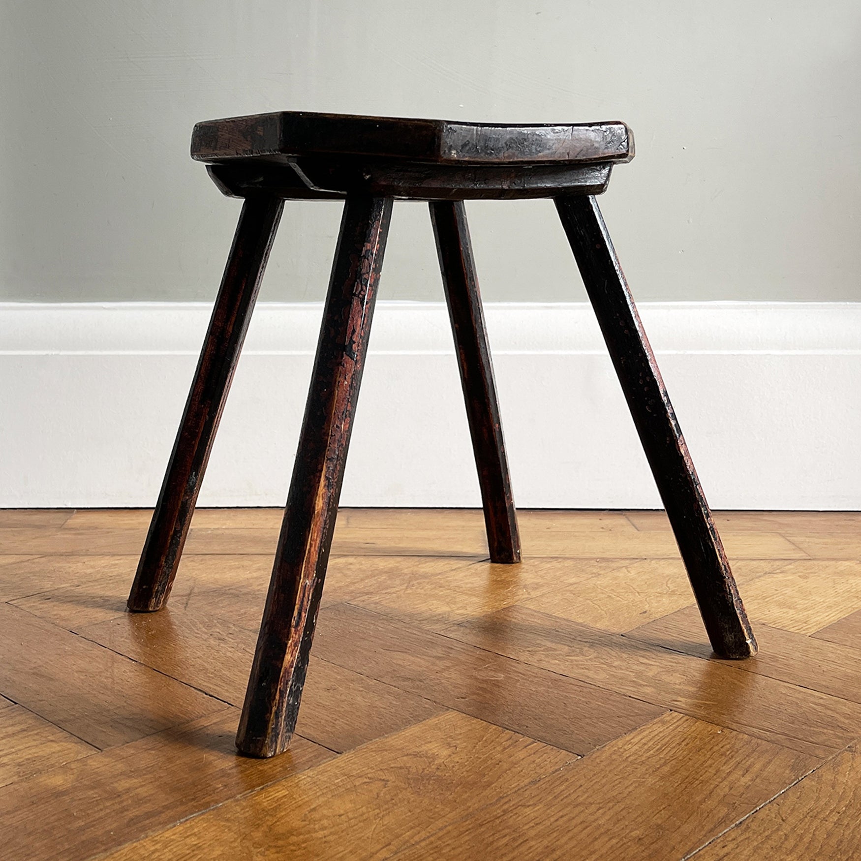 An Antique Elm Milking Stool with a wonder original black painted finish that has worn away over its years of use to provide the perfect finish. Very solid and sitting on four tapered straight edged legs -SHOP NOW - www.intovintage.co.uk